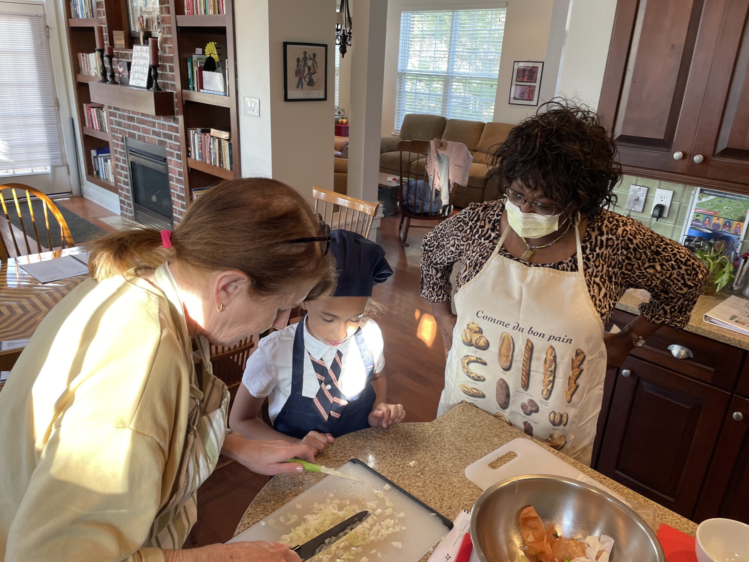 Belinda Rosen demonstrates how to chop an onion for Alyssa Pagan, as Bonita Bell looks on.